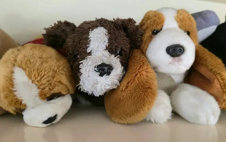 Drie knuffelige opgezette honden met zachte, getextureerde vacht in bruin en wit.